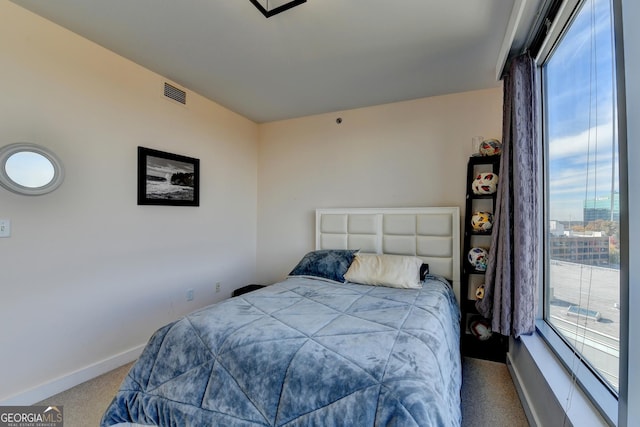 bedroom featuring light colored carpet and multiple windows