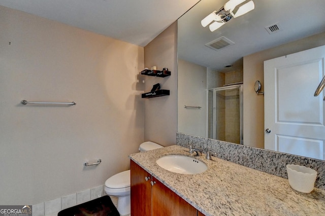 bathroom featuring vanity, toilet, and a shower with shower door