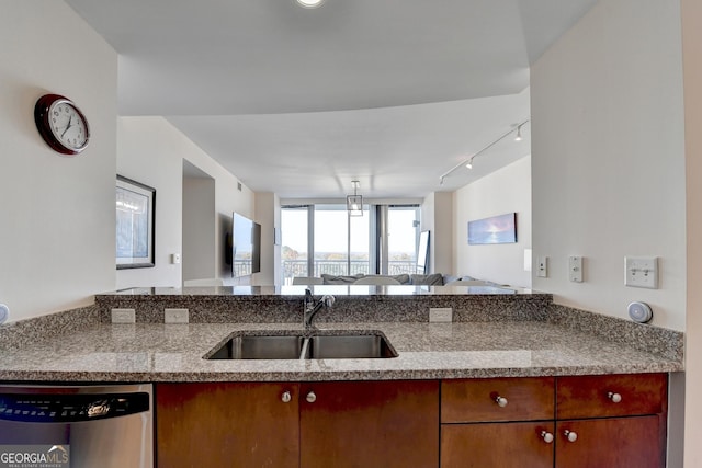 kitchen featuring rail lighting, dishwasher, kitchen peninsula, and sink