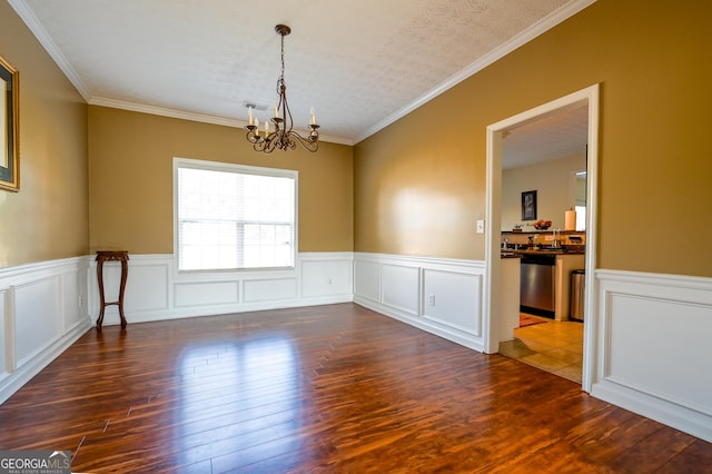 unfurnished room with a notable chandelier, dark hardwood / wood-style floors, ornamental molding, and a textured ceiling