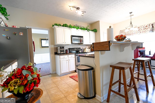 kitchen with white cabinetry, a textured ceiling, appliances with stainless steel finishes, and a chandelier