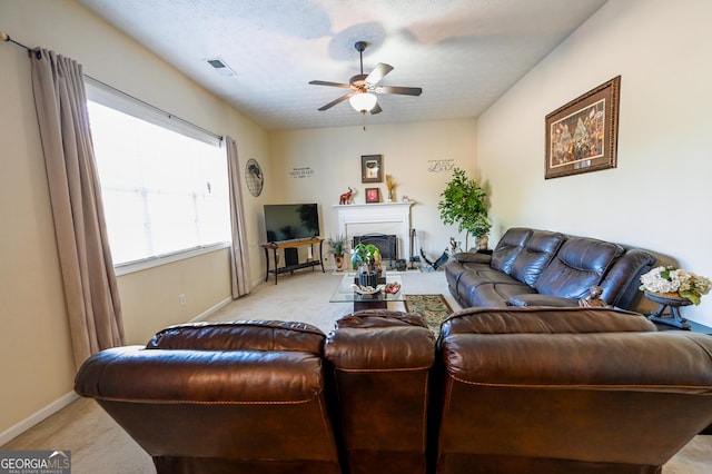 carpeted living room with ceiling fan and a textured ceiling