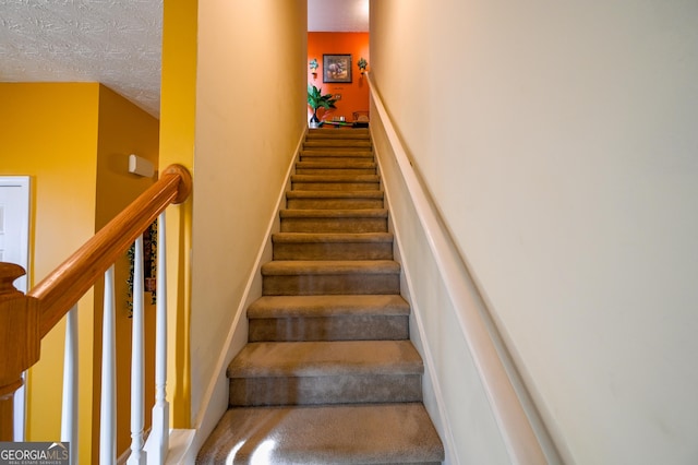 stairway featuring a textured ceiling