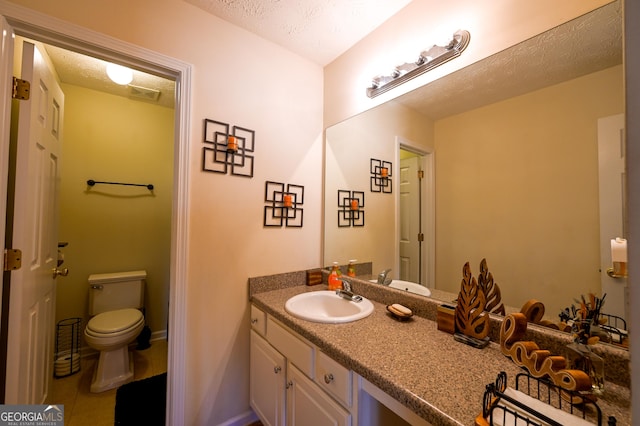 bathroom with tile patterned floors, vanity, a textured ceiling, and toilet