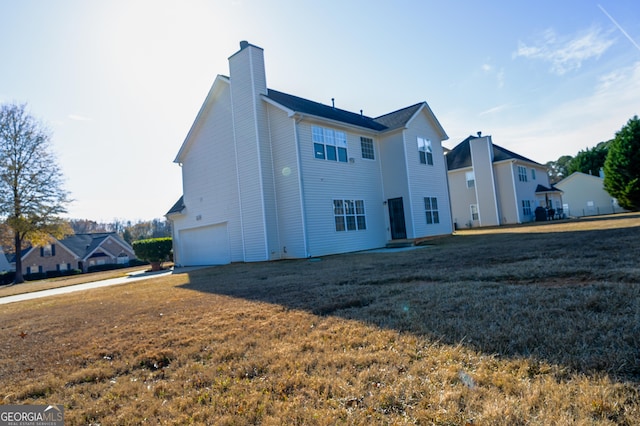 back of house featuring a garage and a lawn