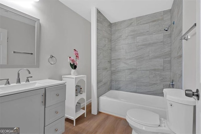 full bathroom featuring hardwood / wood-style floors, vanity, toilet, and tiled shower / bath combo