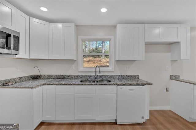 kitchen with dishwasher, white cabinets, light wood-type flooring, and sink