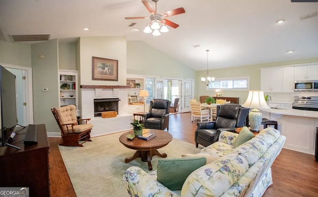 living room featuring ceiling fan with notable chandelier, wood-type flooring, and high vaulted ceiling