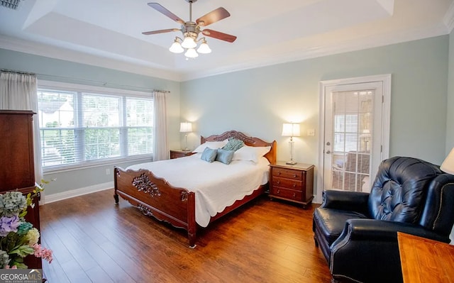 bedroom featuring ceiling fan, crown molding, dark wood-type flooring, and a tray ceiling