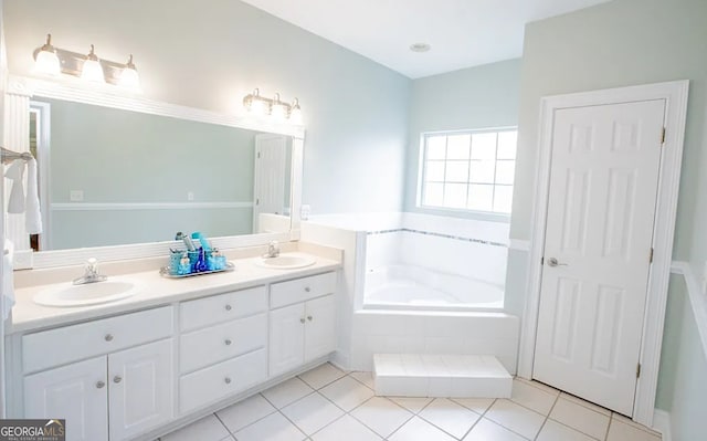 bathroom with tile patterned flooring, vanity, and tiled bath