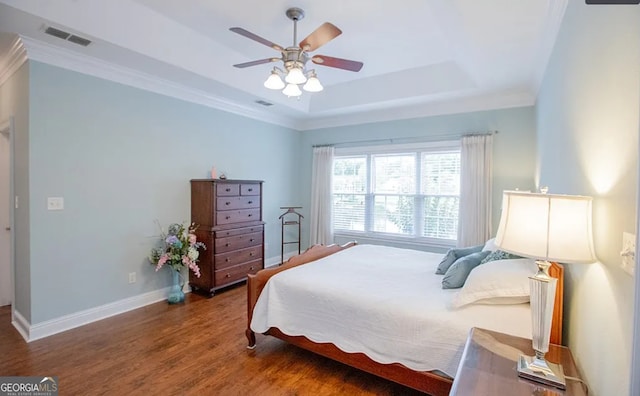 bedroom featuring hardwood / wood-style floors, ceiling fan, ornamental molding, and a tray ceiling