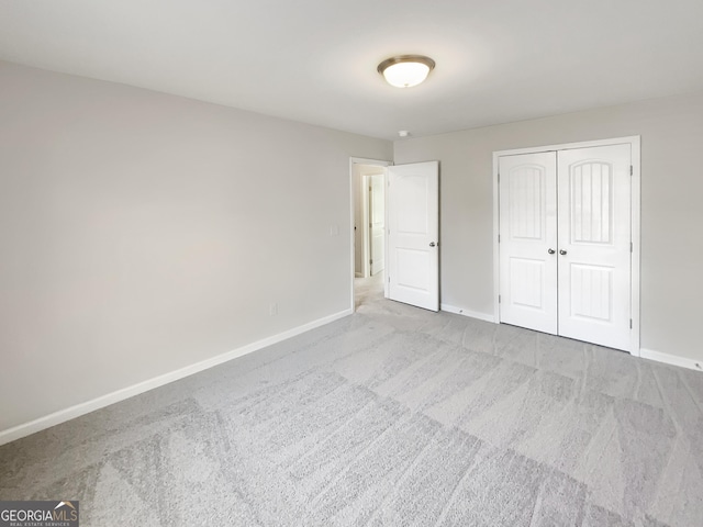 unfurnished bedroom with light carpet and a closet