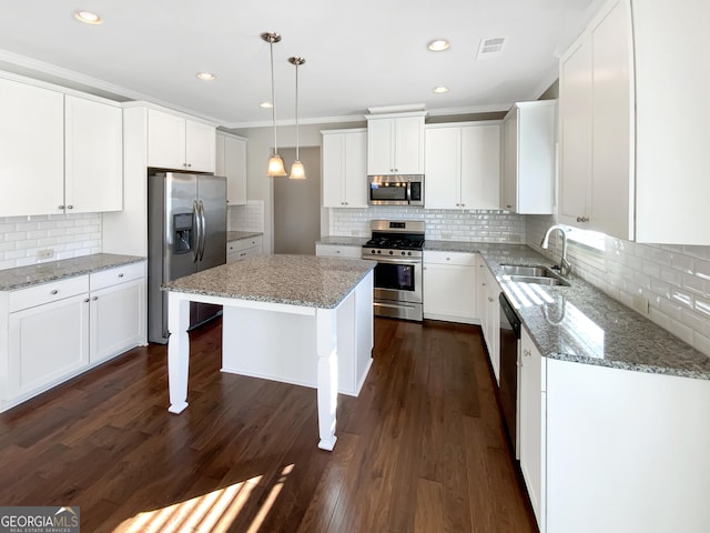 kitchen featuring stainless steel appliances, sink, dark hardwood / wood-style floors, a kitchen island, and hanging light fixtures