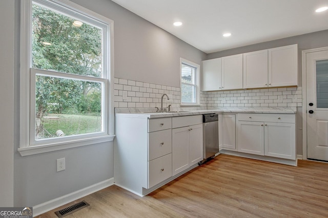 kitchen featuring white cabinets, light wood-type flooring, dishwasher, and backsplash