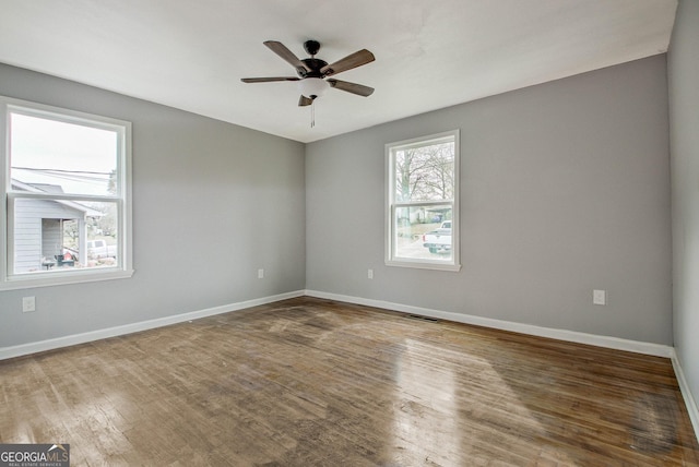 empty room with hardwood / wood-style floors, plenty of natural light, and ceiling fan