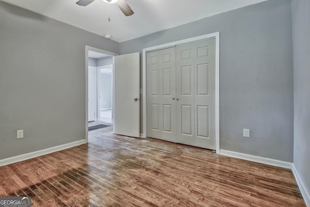 unfurnished bedroom featuring hardwood / wood-style floors, a closet, and ceiling fan