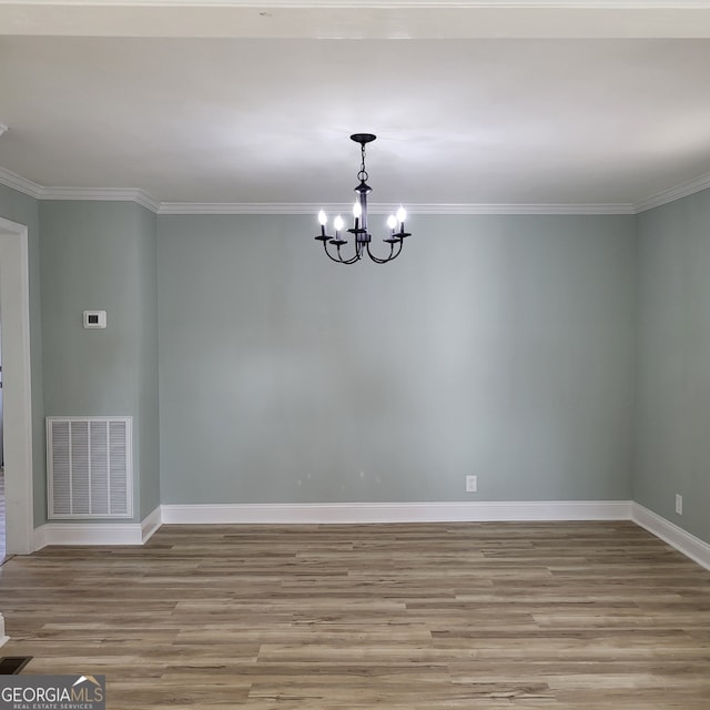 empty room featuring light hardwood / wood-style flooring, an inviting chandelier, and crown molding