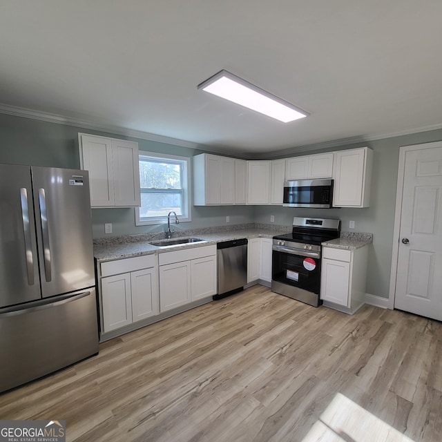 kitchen with white cabinets, light wood-type flooring, stainless steel appliances, and sink