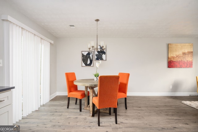 dining space with an inviting chandelier, light hardwood / wood-style floors, and a textured ceiling