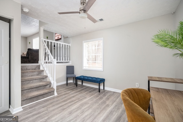 sitting room with ceiling fan, a textured ceiling, and light hardwood / wood-style flooring