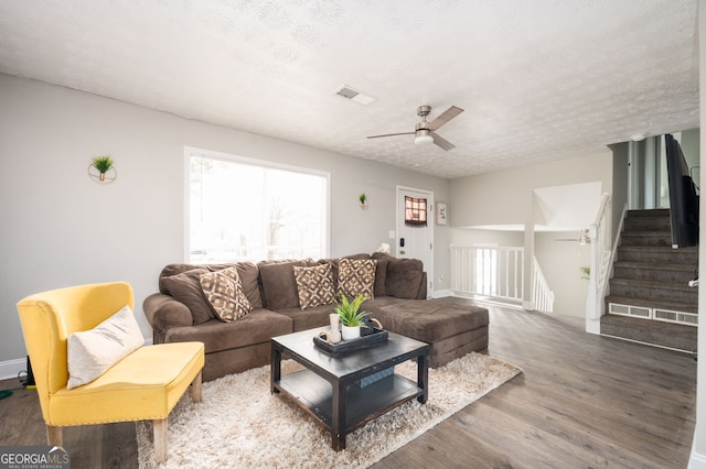 living room featuring ceiling fan, hardwood / wood-style flooring, and a textured ceiling