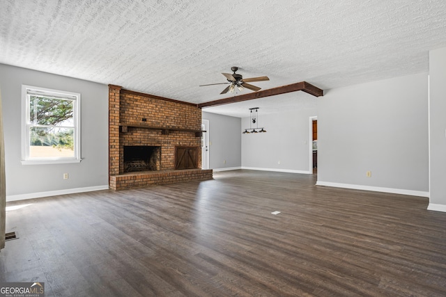 unfurnished living room featuring baseboards, a textured ceiling, a brick fireplace, and dark wood-style flooring