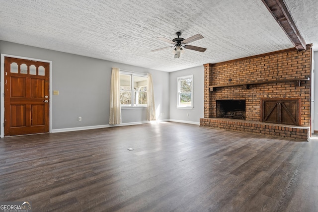 unfurnished living room featuring baseboards, dark wood finished floors, a fireplace, a textured ceiling, and a ceiling fan