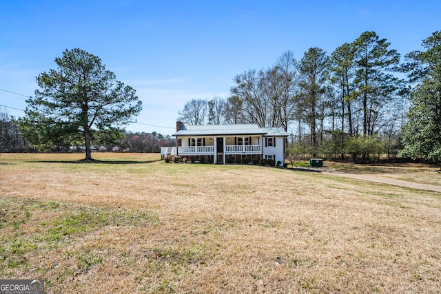 view of front of property with covered porch, a chimney, and a front yard