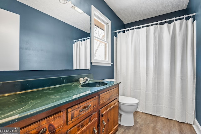 bathroom with a textured ceiling, toilet, vanity, and wood finished floors