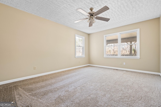 carpeted empty room featuring visible vents, baseboards, a textured ceiling, and a ceiling fan