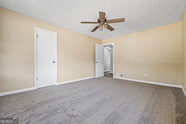 empty room with carpet flooring, baseboards, visible vents, and a textured ceiling