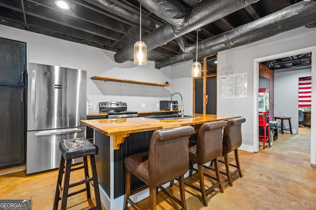 kitchen with a sink, wood counters, open shelves, appliances with stainless steel finishes, and concrete flooring