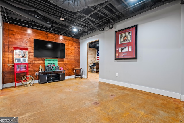 interior space featuring wooden walls, concrete floors, and baseboards