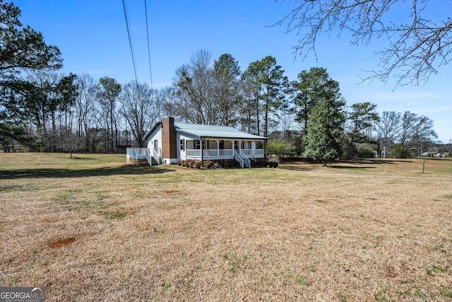 exterior space featuring a front lawn, covered porch, and a chimney