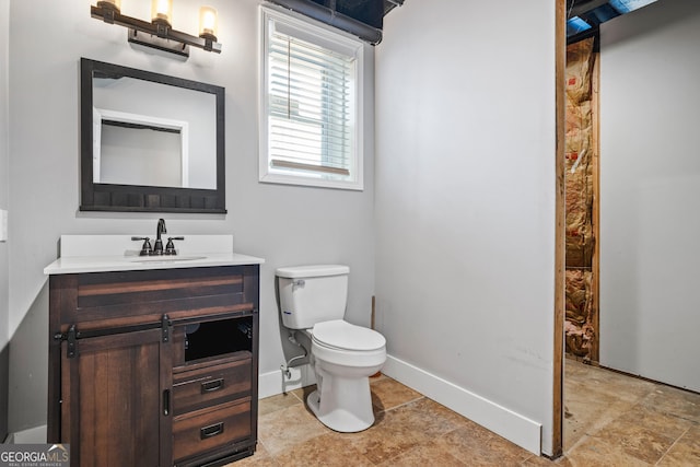 bathroom with toilet, vanity, and baseboards