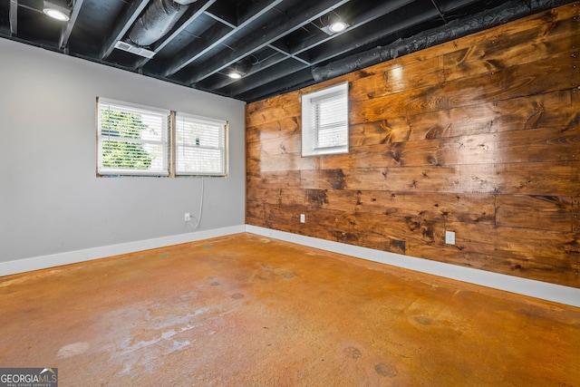 spare room with wood walls, concrete flooring, and baseboards