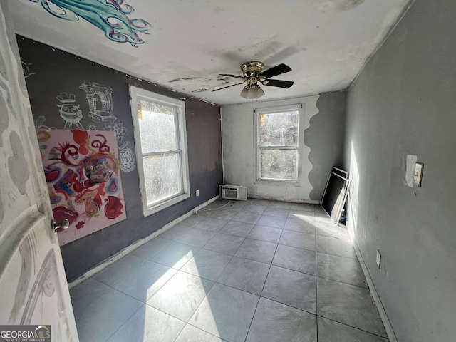 spare room with plenty of natural light, ceiling fan, light tile patterned floors, and a wall unit AC