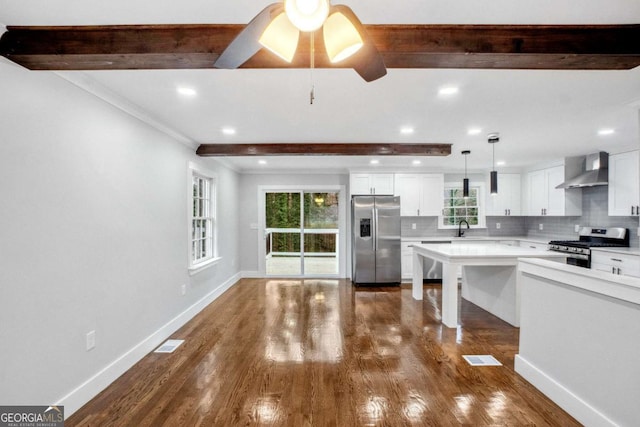 kitchen featuring stainless steel appliances, white cabinetry, a wealth of natural light, and wall chimney range hood