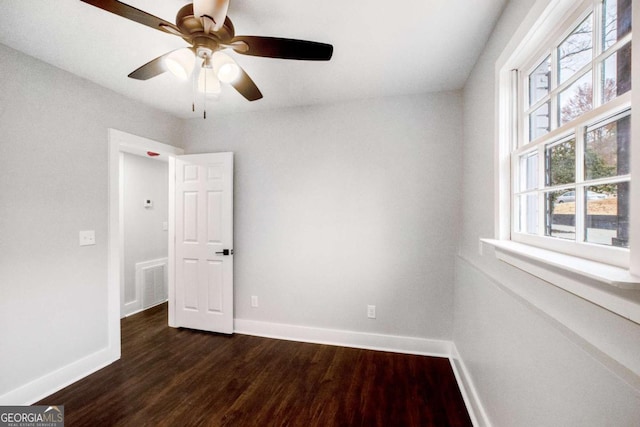 empty room with dark hardwood / wood-style flooring and ceiling fan