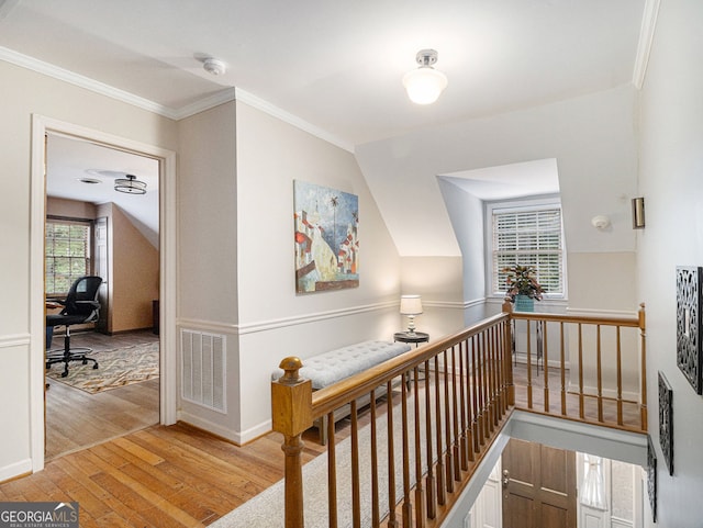 hall featuring visible vents, lofted ceiling, crown molding, an upstairs landing, and light wood-style floors