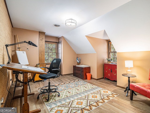 home office with vaulted ceiling, wood finished floors, visible vents, and baseboards