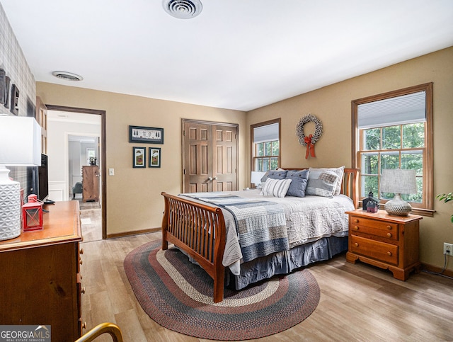 bedroom with light wood-type flooring, visible vents, and multiple windows