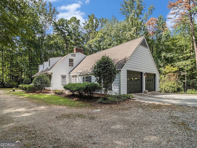 view of front of house with driveway, a chimney, roof with shingles, an attached garage, and fence