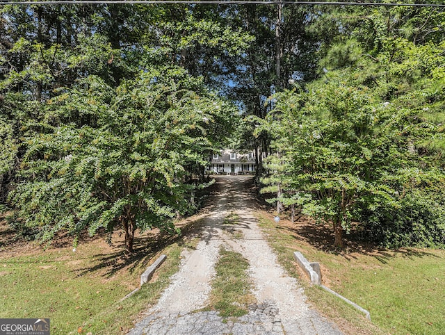 view of road with driveway and a view of trees