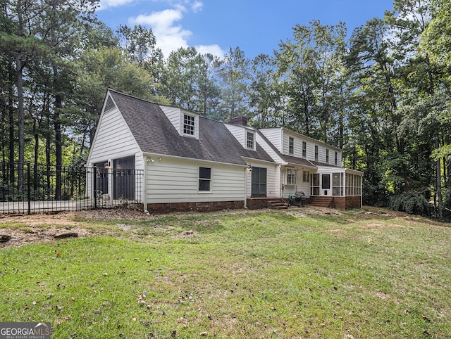 rear view of house with a garage, a sunroom, a chimney, fence, and a yard