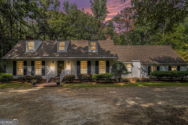 cape cod-style house with a porch and a chimney