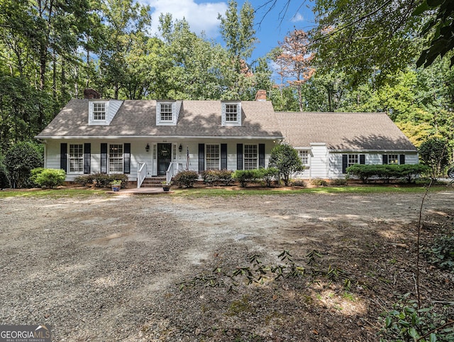 cape cod-style house with a porch and a chimney