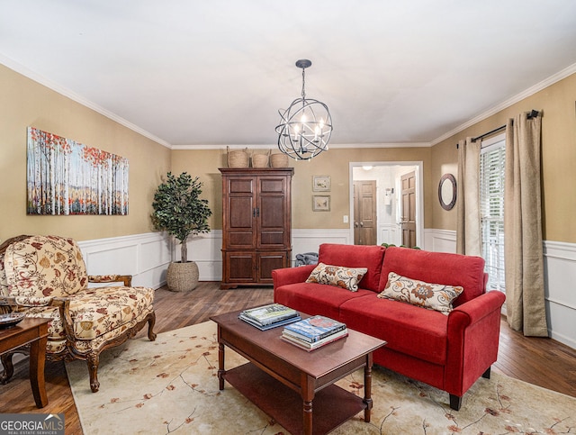 living area with a chandelier, a wainscoted wall, crown molding, and wood finished floors