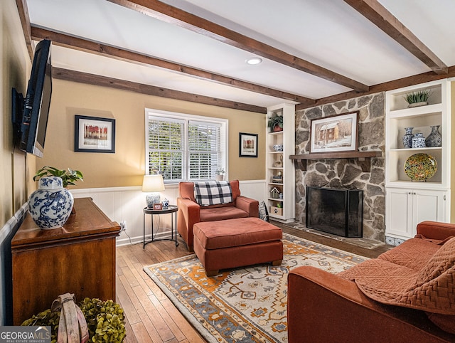 living room with built in features, wainscoting, a fireplace, and light wood finished floors