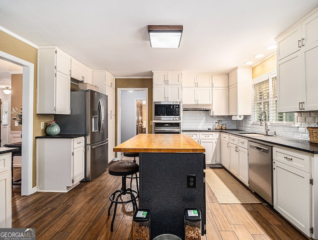 kitchen featuring decorative backsplash, dark wood-style floors, appliances with stainless steel finishes, wooden counters, and a sink